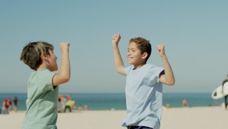 Medium-shot-of-boys-rejoicing-over-victory-in-football-on-beach